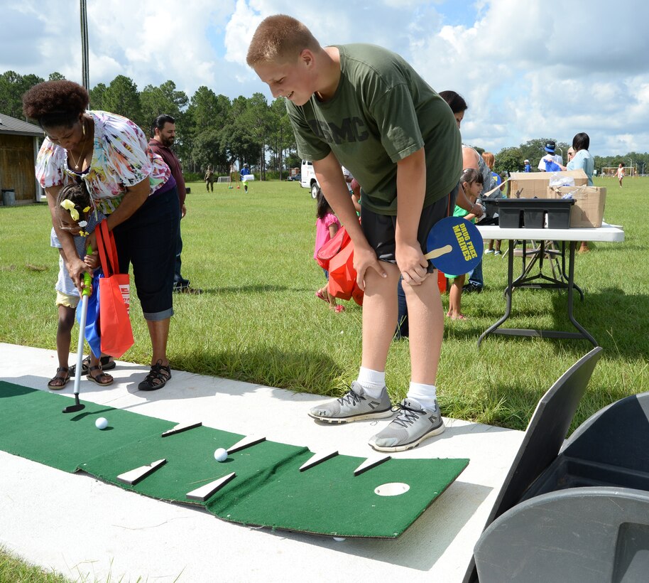 A parent assists her child in hitting a golf ball after participating in Marine Corps Logistics Base Albany’s Summer Reading Awards Program at Covella Pond, Aug. 20.