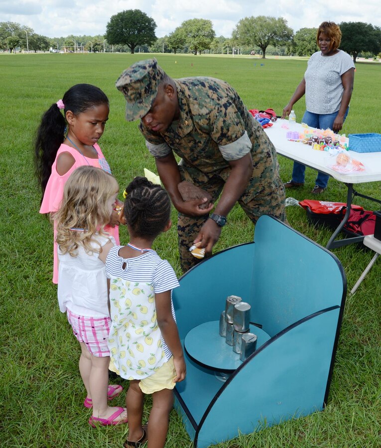 Major Lee Taylor, retired, keynote speaker, Marine Corps Logistics Base Albany’s Summer Reading Program, assists several children play games after the conclusion of the summer reading awards program at Covella Pond, Aug. 20.