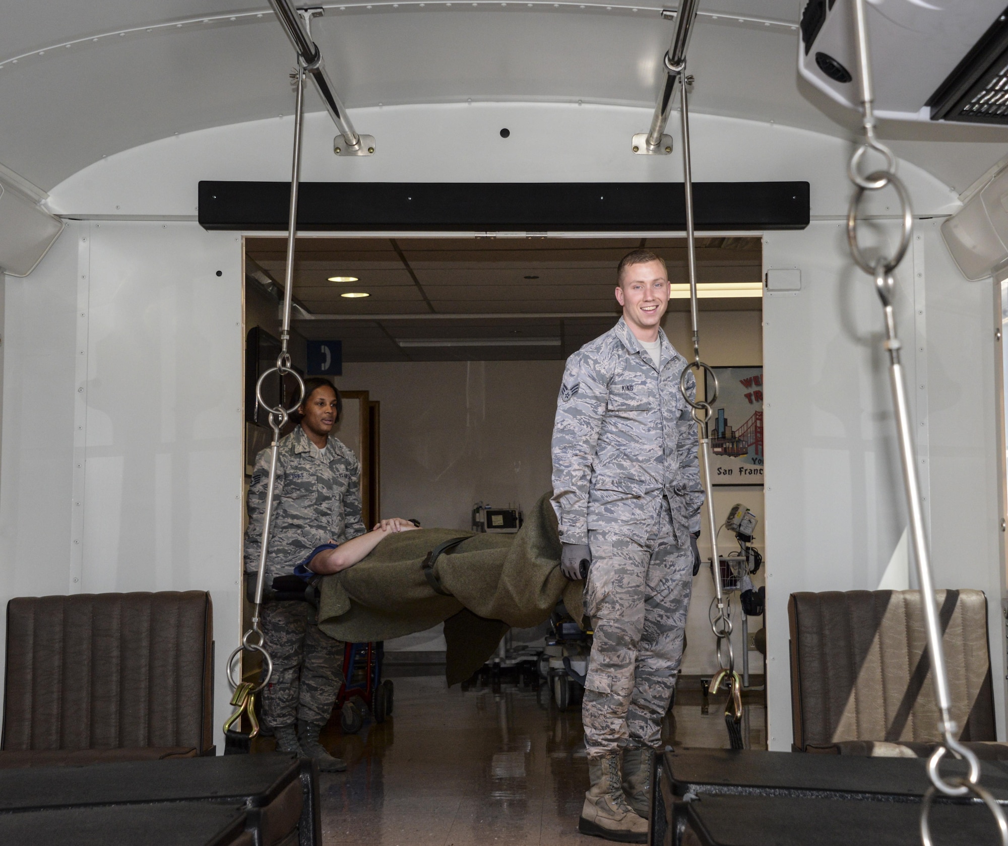 Senior Airman Adam King and Staff Sgt. Katrevious Swift, 60th IPTS health service management technicians, load a patient onto an ambus Aug. 23 at Travis Air Force Base, Calif. The En-route Patient Staging Facility Flight provides support and continues medical care for patients coming in from or going out to an aircraft. 
