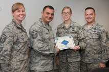 Master Sgt. Nicholas Souza, center, Air Force Life Cycle Management Center Detachment 7 first sergeant, presents the Diamond Sharp Award to Staff Sgt. Autumn Bogert, Battle Management NCO in charge Operations Management, in Building 1624, Aug. 24, while Master Sgts. Jessica LaBrie, 66th Air Base Group first sergeant, and Richard Abbott, 66th Security Forces Squadron first sergeant, look on. The Diamond Sharp program, adopted by the First Sergeant Council, aims to recognize Airmen in the grades of airman basic through technical sergeant. (U.S. Air Force photo by Mark Herlihy)
