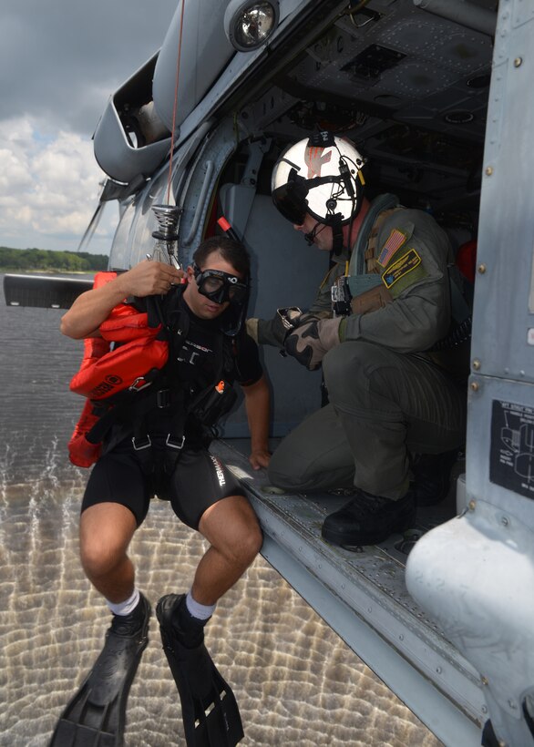 Navy Petty Officer Class Chris Nelson, crew chief, prepares to lower Navy Petty Officer 1st Class Harrison Greenmaki into the waterduring training at Naval Support Activity Panama City, Fla., Aug. 24, 2016. Greenmaki is a search and rescue swimmer. Navy photo by Petty Officer 2nd Class Fred Gray IV