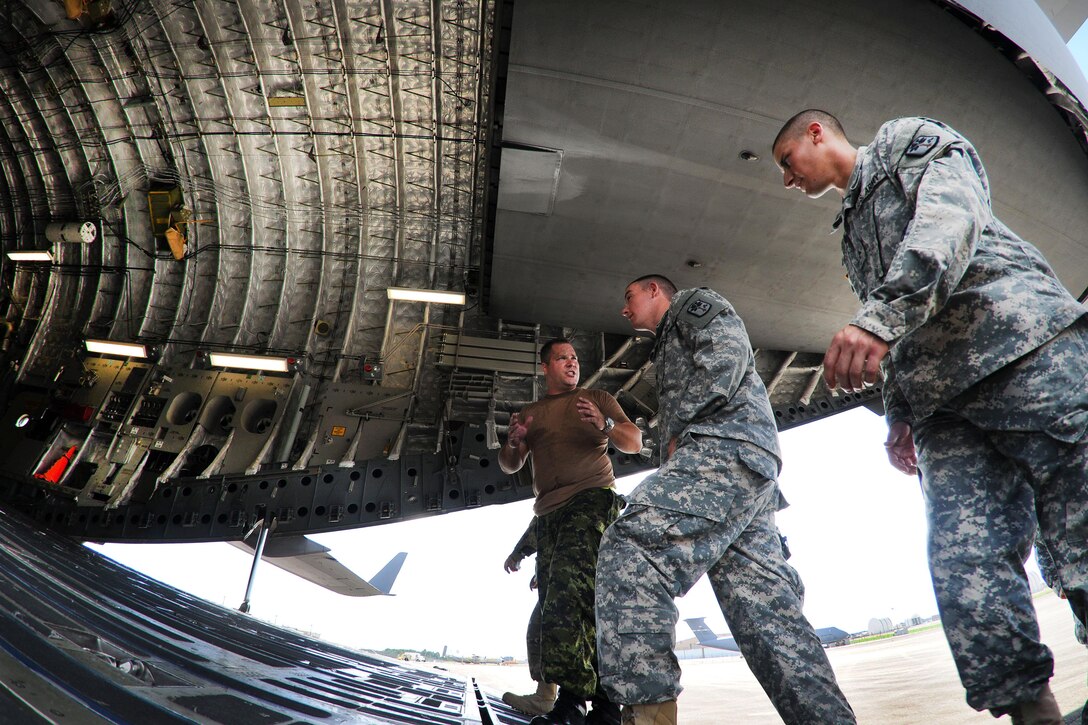 U.S. and Canadian soldiers discus different techniques and methods for uploading vehicles onto an Canadian air force Globemaster III aircraft in Greenville, S.C., Aug. 13, 2016. Army National Guard photo by Staff Sgt. Roby Di Giovine