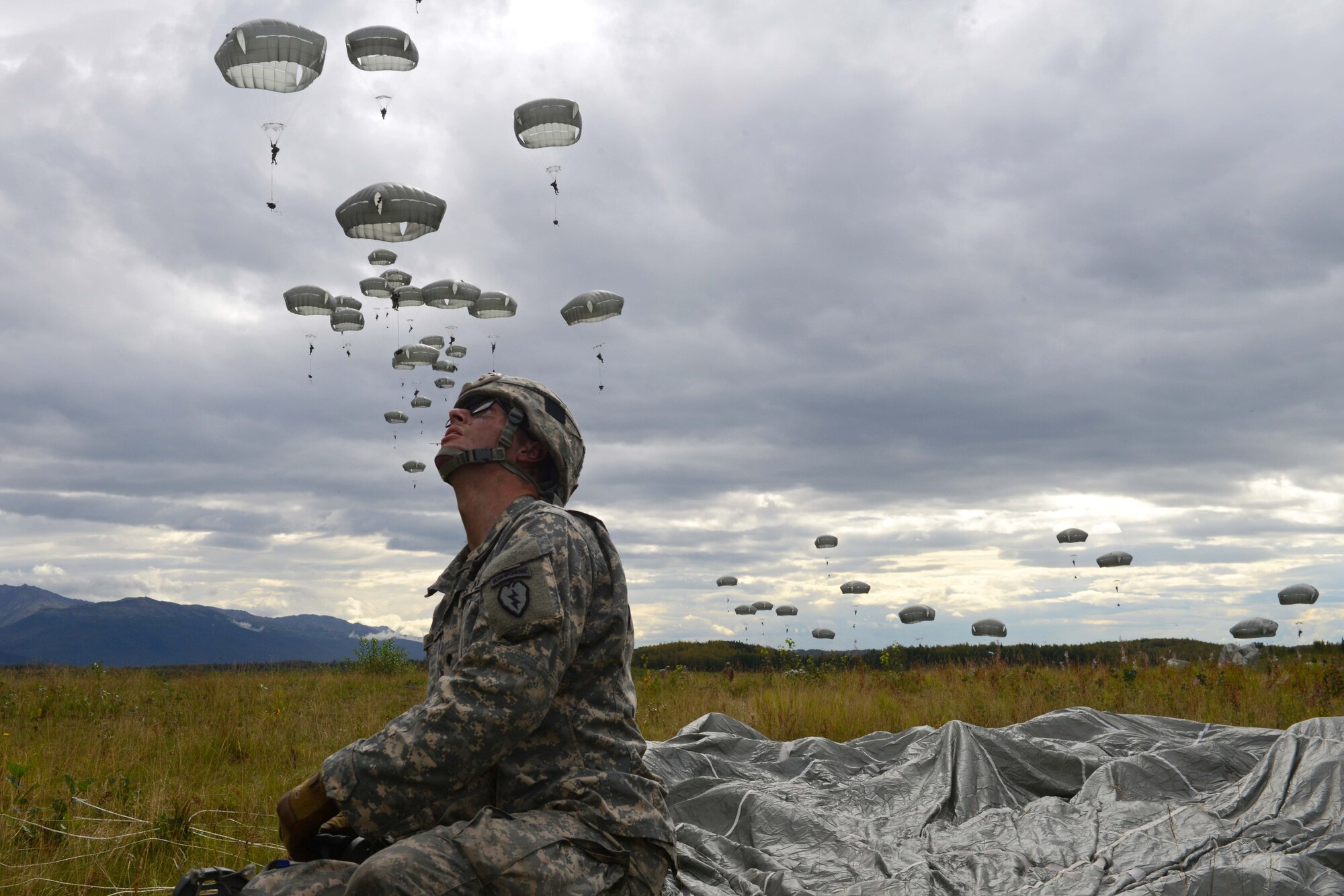 A paratrooper assigned to 1st Battalion, 501st Parachute Infantry Regiment, 4th Infantry Brigade Combat Team (Airborne), 25th Infantry Division, U.S. Army Alaska, inspects the sky for incoming paratroopers during a joint forcible entry exercise at Malemute Drop Zone on Joint Base Elmendorf-Richardson, Alaska, Aug. 23, 2016, as part of Exercise Spartan Agoge. Spartan Agoge is a brigade-level field training exercise that began Aug. 15, focused on an array of combat-related tasks from squad live-fire exercises to helicopter air insertion and airborne training. (U.S. Air Force Airman 1st Class Javier Alvarez)