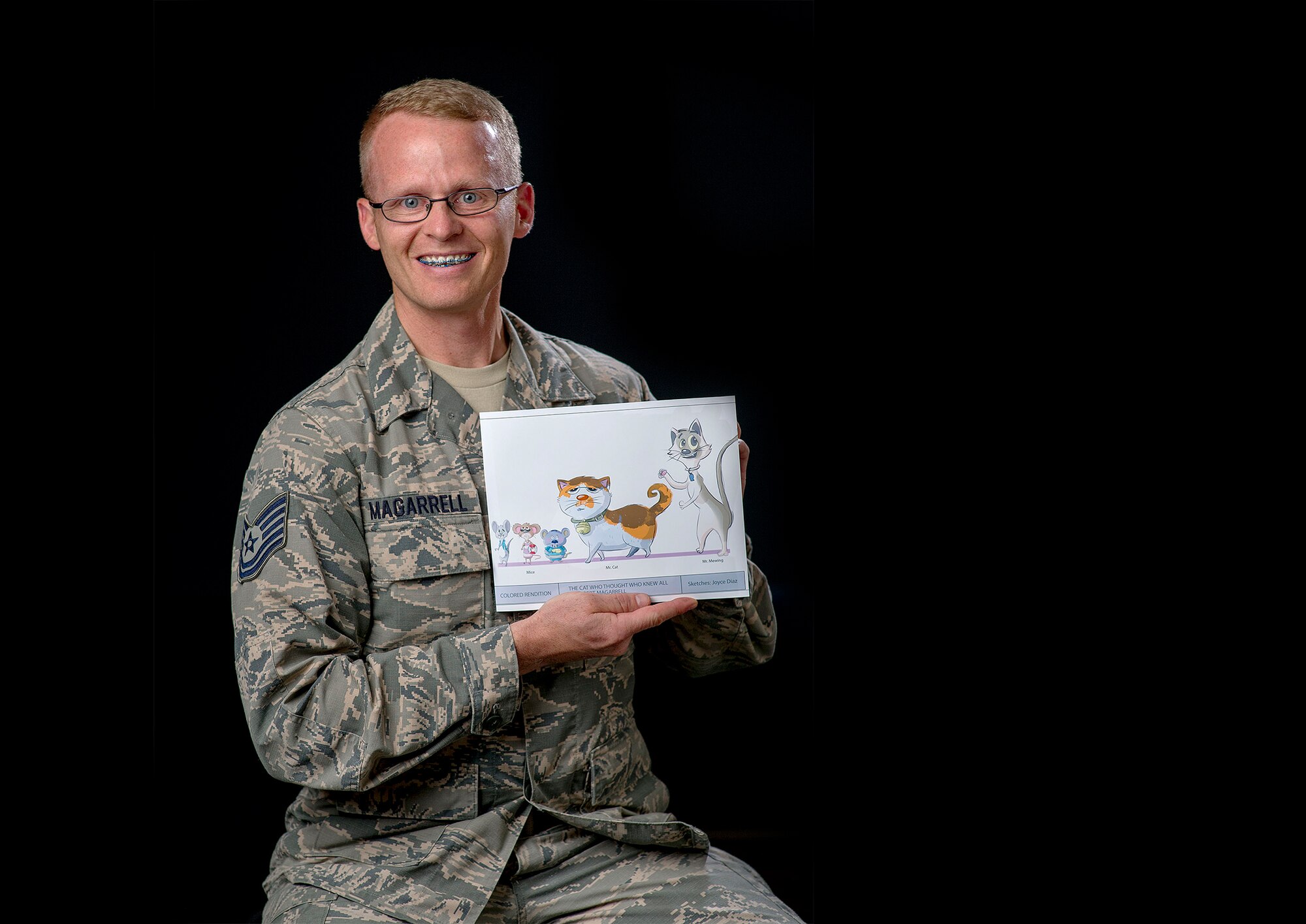 Tech. Sgt. Robert Magarrell, 60th Civil Engineer Squadron, poses for a photo with a picture of the characters from his soon-to-be published children's book, "Mr. Cat and the Mat," Aug. 16 at Travis Air Force Base, Calif. Magarrell came up with the idea for the children's book 12 years ago as a way to cope with the passing of his father. (U.S. Air Force photo by T.C. Perkins Jr.)