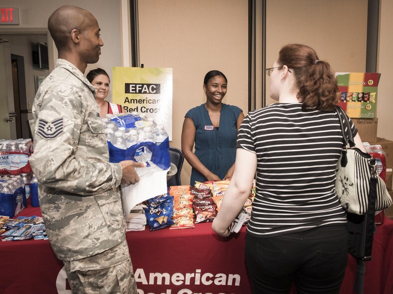 Tech. Sgt. Derrick James and wife, Melanie, pick up supplies from the American Red Cross during contingency housing in-processing at Yokota Air Base, Japan, Aug 23, 2016. Eastside tower residents lost power in their homes during Tropical Storm Mindulle and relocated to contingency housing until the 374th Civil Engineer Squadron personnel could restore power and ensure a safe living environment. (U.S. Air Force photo by Airman 1st Class Baker/Released)