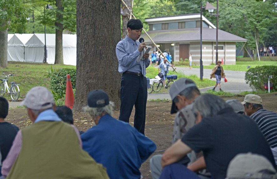A member of a local church reads a passage from a bible at Ueno Park, Tokyo, Japan, Aug. 19, 2016. The Yokota Air Base Chapel has worked with local churches for approximately 10 years to provide help for homeless people. (U.S. Air Force photo by Senior Airman David Owsianka/Released)