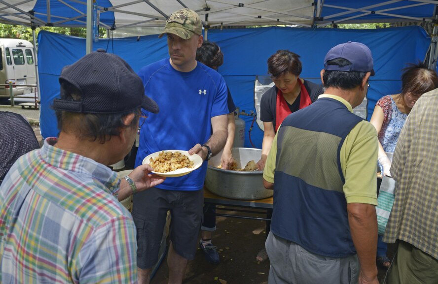 Tech. Sgt. Aleric Hebert, 374th Wing Staff Agencies chapel resource management NCO in charge, hands food to a homeless man at Ueno Park, Tokyo, Japan, Aug. 19, 2016. Members of Yokota Air Base and a local church come together once a month to provide food and haircuts for the homeless. (U.S. Air Force photo by Senior Airman David Owsianka/Released)