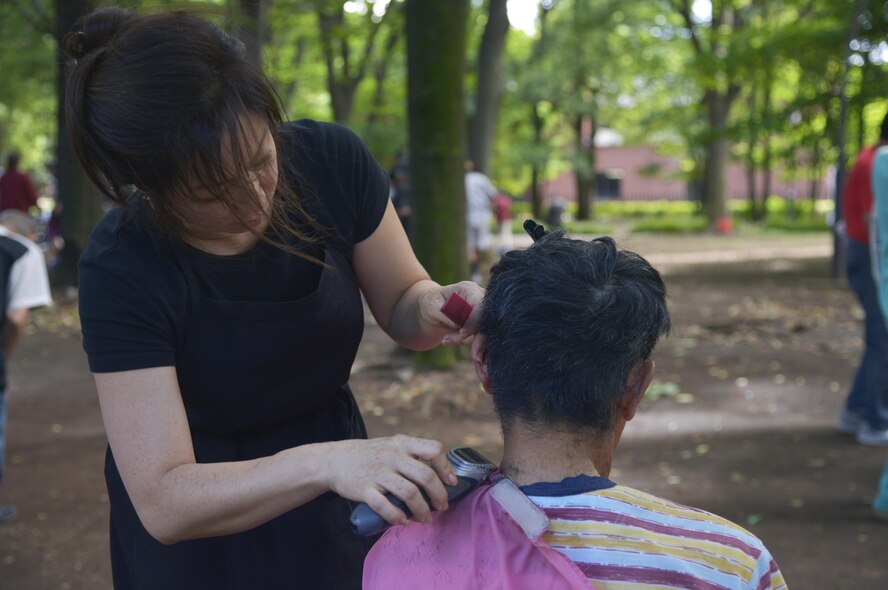 A member of a local church give a haircut to a homeless man at Ueno Park, Tokyo, Japan, Aug. 19, 2016. The Yokota Air Base Chapel has worked with local churches for approximately 10 years to provide help for homeless people. (U.S. Air Force photo by Senior Airman David Owsianka/Released)