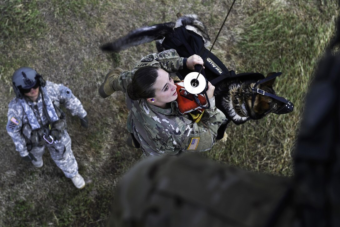 Army Spc. Mariah Ridge, a military working dog handler, and her dog, Jaska, ride a hoist to a UH-60L Black Hawk helicopter during K-9 hoist evacuation training at Soto Cano Air Base, Honduras, Aug. 15, 2016. Ridge is assigned to Joint Task Force Bravo’s Joint Security Forces. Air Force photo by Staff Sgt. Siuta B. Ika