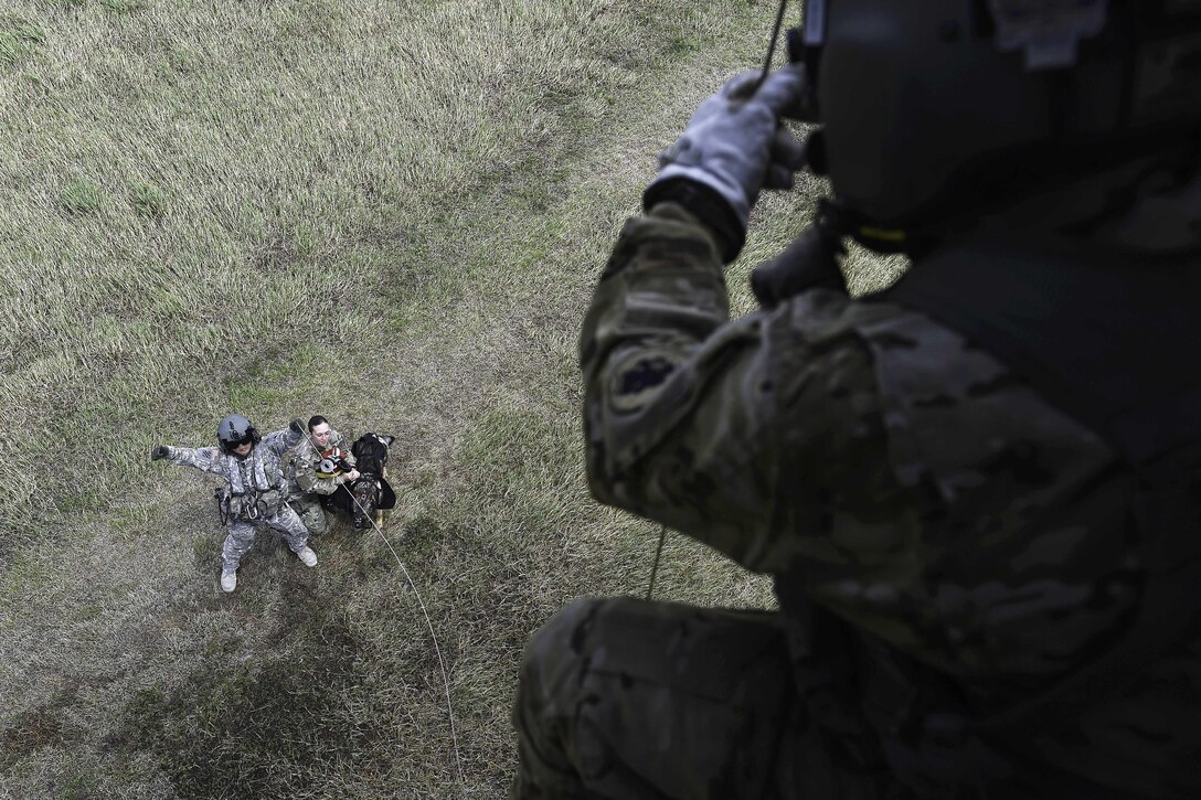Army Staff Sgt. Jun Ma, left, signals to Spc. Andrew Briones to raise a hoist attached to Spc. Courtney Moreland, a military working dog handler, and her dog, Puma, during K-9 hoist evacuation training at Soto Cano Air Base, Honduras, Aug. 15, 2016. Ma is a flight paramedic and Briones is a crew chief assigned to the 1st Battalion, 228th Aviation Regiment. Moreland is assigned to Joint Task Force Bravo’s Joint Security Forces. Air Force photo by Staff Sgt. Siuta B. Ika