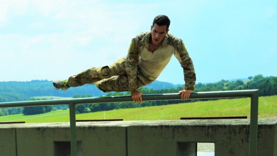 Maj. Pete Grossenbach using near perfect form to vault the “over” bar of the “over-and-udders” that immediately follow the slide through the concrete “pillbox” visible behind Grossenbach.