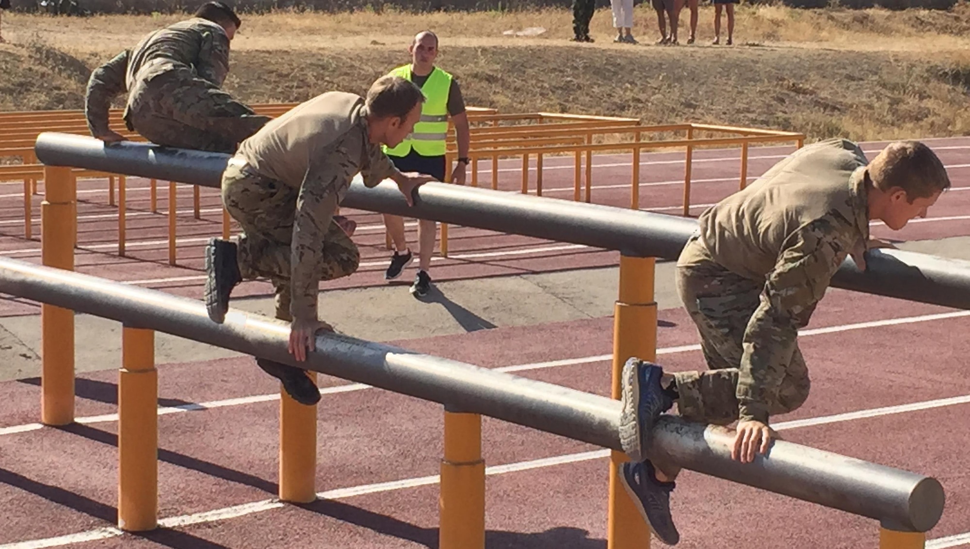 Team USA 3 tackles the second obstacle on the 500 meter, NATO-standard, obstacle course.  Each member must touch one foot between the two bars and then vault the higher bar.  (L to R)1st Lt. Sterling Broadhead, Capt. Chuck Francis and 2nd Lt. Nate Davis (Mississippi Army National Guard).