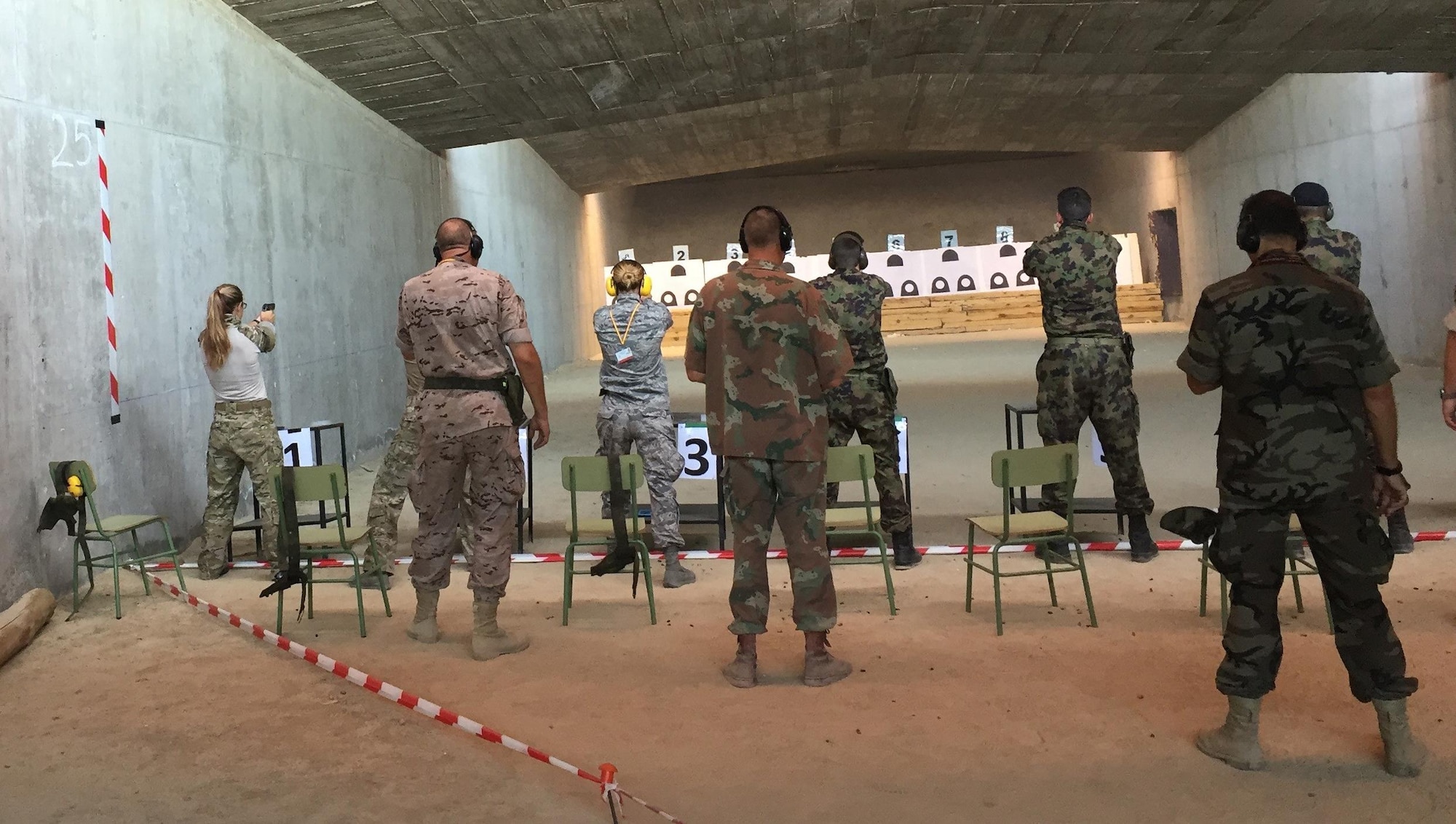 Major Caitlin Harris and Capt. Amy Moore of Team USA 2 take careful aim on the indoor pistol range.  Three competitors from another team shoot at the same time with one coach per team allowed to observe. 