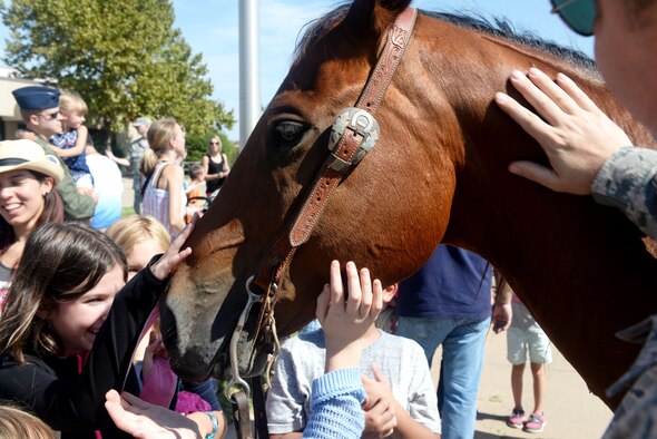 Families and children gather around a horse during the 18th Annual Cattle Drive, Aug. 25, 2016, at Altus Air Force Base, Okla. Approximately 18 Texas Longhorn cattle were driven through Altus AFB at this year's base Cattle Drive which provided opportunity for community members to share part of their culture with the Airmen and their families. (U.S. Air Force photo by Airman Jackson N. Haddon/Released).
