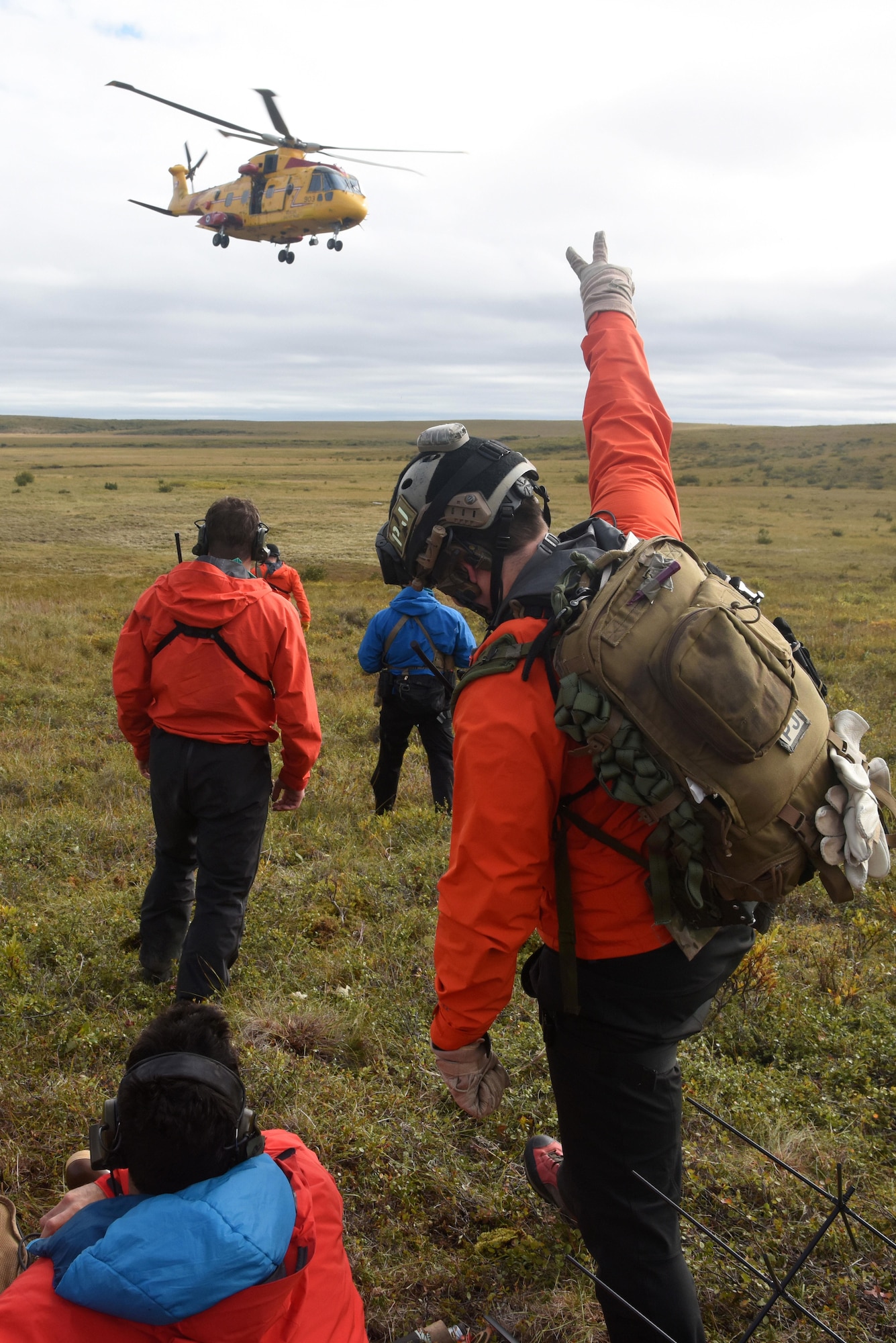 Technical Sgt. Cody Inman, a pararescueman with the 212th Rescue Squadron, Joint Base Elmendorf-Richardson, Alaska, waves to Royal Canadian Airmen during Exercise Arctic Chinook Aug. 24, 2016.  Exercise Arctic Chinook is a joint U.S. Coast Guard and U.S. Northern Command-sponsored exercise on the U.S. State Department approved list of Arctic Council Chairmanship events. The Arctic mass rescue operation exercise scenario consisted of an adventure-class cruise ship with approximately 200 passengers and crew that experience a catastrophic event with the need to abandon ship. Arctic Chinook exercised elements of the Arctic Search and Rescue Agreement to include interoperability, cooperation, information sharing, SAR services, and joint exercise review.