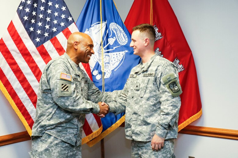 Col. Vincent Quarles, commander of the Middle East District, presents Hunter Tuttle, an Army Reserve Officer Training Corps cadet, with a coin upon completion of Tuttle's internship with the district.