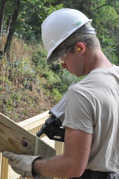 Staff Sgt. Dominick Tami, a Civil Engineer structural engineer, uses a nail gun to secure a piece of treated lumber to the new staircase leading from the Veteran’s Park to the riverside here, Aug. 25, 2016. Tami is a member of a small team from the 910th Civil Engineer Squadron, based at nearby Youngstown Air Reserve Station (YARS), Ohio, who teamed up with the City of Newton Falls to undertake a three-week project to demolish the existing staircase and design and build the new stairs under Department of Defense’s Realistic Military Training program and the Air Force Community Partnership Program. The program is designed to identify and develop mutually beneficial partnerships between Air Force installations and surrounding communities. (U.S. Air Force photo/Master Sgt. Bob Barko Jr.)