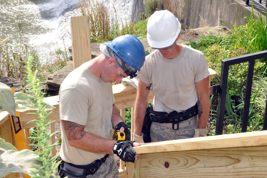 Senior Airman Mike Dibble, a Civil Engineer structural engineer, measures a piece of treated lumber on the new staircase leading from the Veteran’s Park to the riverside here, Aug. 25, 2016, while Staff Sgt. Dominick Tami, also a Civil Engineer structural engineer, observes his work. Dibble and Tami are members of a small team from the 910th Civil Engineer Squadron, based at nearby Youngstown Air Reserve Station (YARS), Ohio, who teamed up with the City of Newton Falls to undertake a three-week project to demolish the existing staircase and design and build the new stairs under Department of Defense’s Realistic Military Training program and the Air Force Community Partnership Program. The program is designed to identify and develop mutually beneficial partnerships between Air Force installations and surrounding communities. (U.S. Air Force photo/Master Sgt. Bob Barko Jr.)