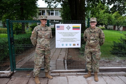 SIAULIAI, Lithuania – Army Reserve Soldiers from the 7th Mission Support Command helped coordinate the construction of a new fence and gate and sign for the local ‘infant’ or ‘baby’ orphanage with USAR Soldiers from the 412th Theater Engineer Command and Lithuanian Soldiers and Airmen and local national contractors, Aug. 8-25, 2016. 
Sgt. Elizabeth Prairie, intel analyst with the Company A, 457th CA BN, 361st Civil Affairs Brigade, 7th MSC and Spc. Stephanie Lish, civil affairs specialist, 457th CA BN., Co. A, stand in front of the commemorative plaque attached to the new fence.  
 (Photo by Sgt. 1st Class Matthew Chlosta, 7th MSC Public Affairs Office)