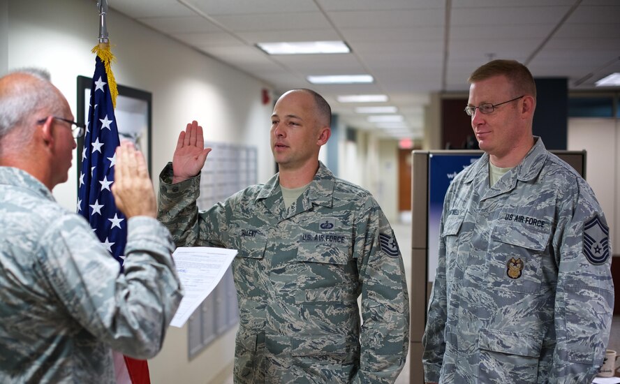 At center, Tech. Sgt. Dennis Talent, financial management craftsman at the 932nd Airlift Wing, raises his right hand to read the oath and reenlist for two more years as his colleague Senior Master Sgt. Wayne Cantwell, supports his decision to continue serving in the Air Force Reserve Command.  (U.S. Air Force photo by Christopher Parr) 
