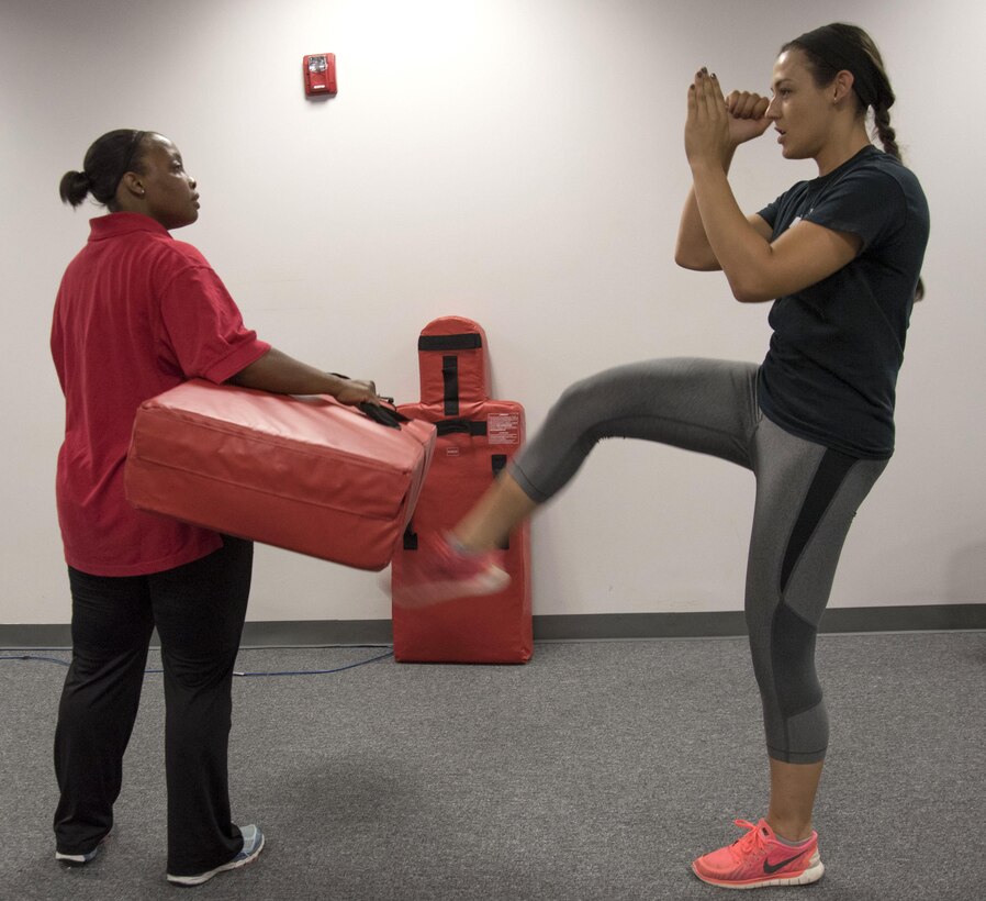 Senior Airman Emily Pearce, 11th Security Forces Squadron response force leader, delivers a kick to a bag held by Staff Sgt. Shandralekha Carlos, 11th Wing Commander's Action Group NCO in charge, during a Rape Aggression Defense class at Joint Base Andrews, Md., Aug. 20, 2016. The R.A.D. class is a self-defense program teaching basic self-defense tactice and avoidance techniques for risk factors. (U.S. Air Force photo by Airman 1st Class Rustie Kramer)