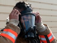 A firefighter with the 5th Civil Engineer Squadron puts on his mask during a training exercise at the fire department training pit on Minot Air Force Base, N.D., Aug. 24, 2016. During training, firefighters are monitored to ensure they’re using proper techniques and maintaining their safety. (U.S. Air Force photo/Airman 1st Class Jonathan McElderry)