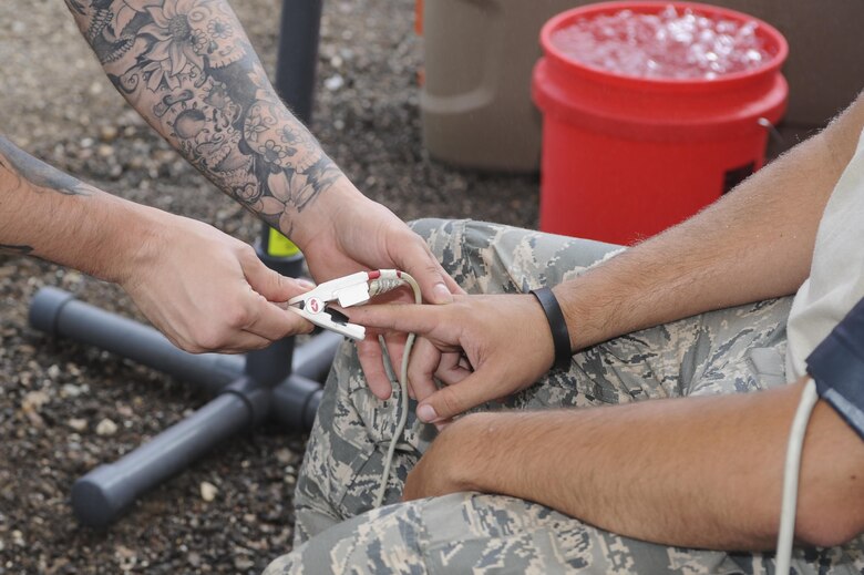A U.S. Air Force firefighter assigned to the 355th Civil Engineer Squadron checks the vitals of another Airman during live-fire training at Davis-Monthan Air Force Base, Ariz., Aug. 26, 2016. Members of the 355th CES’s Fire and Emergency Services and the Green Valley Fire District participated in live-fire Class A training over the course of four days on D-M AFB’s fire training grounds. (U.S. Air Force photo by Airman 1st Class Mya M. Crosby)