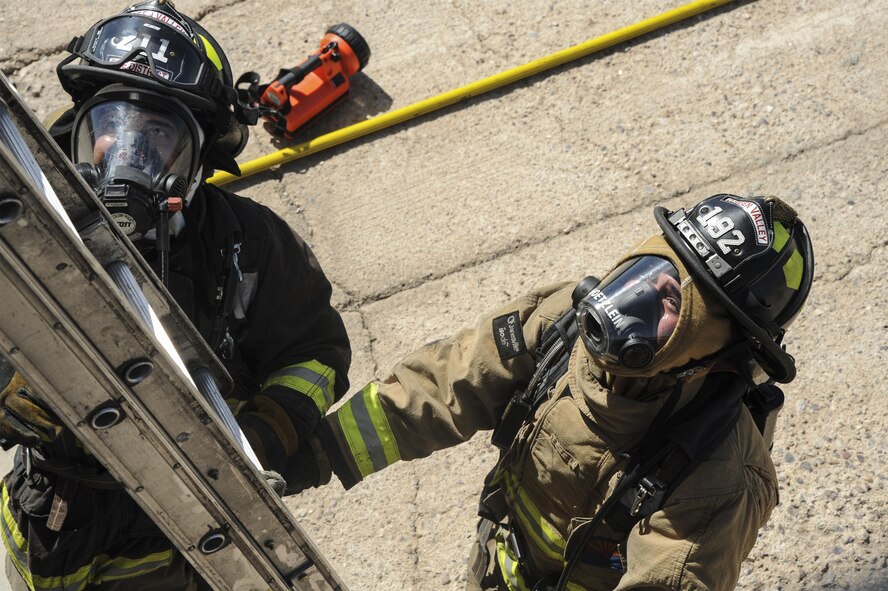 Firefighters from the Green Valley Fire District position a ladder during live-fire training at Davis-Monthan Air Force Base, Ariz,. Aug. 24, 2016. Members of the 355th Civil Engineer Squadron’s Fire and Emergency Services and the Green Valley Fire District participated in live-fire Class A training over the course of four days on D-M AFB’s fire training grounds. (U.S. Air Force photo by Airman 1st Class Mya M. Crosby)