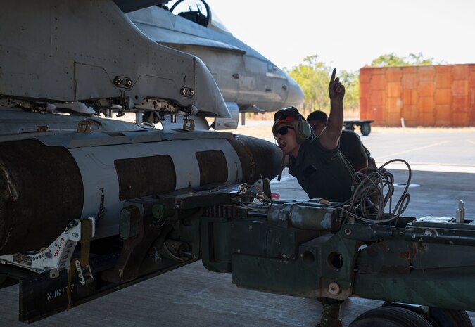 U.S. Marine Corps Lance Cpl. Trevor Serenelli, ordnance Marine assigned to Marine Fighter Attack Squadron (VMFA) 122, shouts directions while guiding a bomb onto an aircraft during Southern Frontier at Royal Australian Air Force Base Tindal, Australia, Aug. 26, 2016. VMFA-122 delivered munitions while providing close air support to ground combat units at Bradshaw Range Complex during the training. Southern Frontier is a three week unit level training evolution helping the flying squadron gain qualifications and experience in low altitude, air ground, high explosive ordnance delivery. (U.S. Marine Corps photo by Cpl. Nicole Zurbrugg)