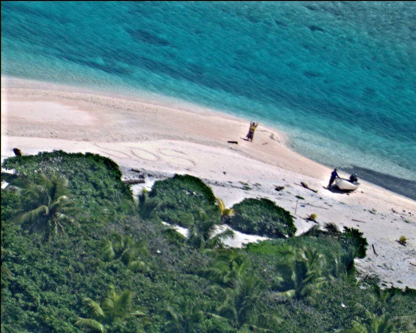 EAST FAYU ISLAND, Micronesia (Aug. 25, 2016) A pair of stranded mariners signal for help by writing "SOS" in the sand as a U.S. Navy P-8A Poseidon aircraft crew from Patrol Squadron (VP) 8 flies over in support of a Coast Guard search and rescue mission. (U.S. Navy photo/Released)