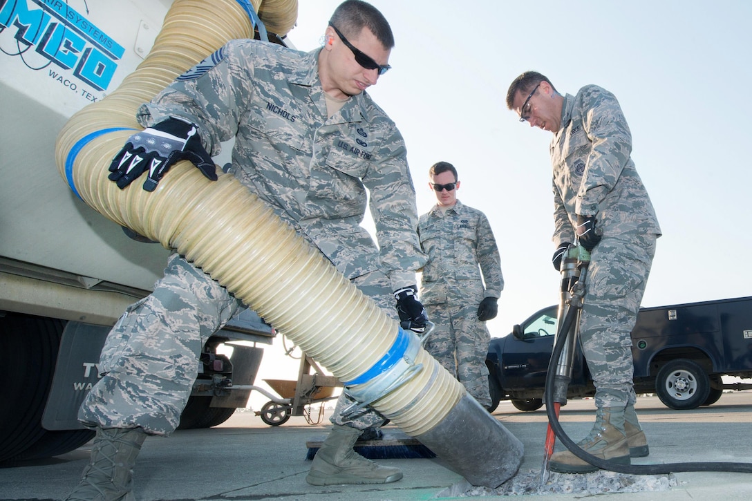 Air Force Col. John Klein, right, commander of the 60th Air Mobility Wing; and Air Force Chief Master Sgt. Steve Nichols, command chief of the 60th Air Mobility Wing; repair a section of concrete on the flightline during the Works With Airmen program at Travis Air Force Base, Calif., Aug. 19, 2016. Air Force photo by Louis Briscese