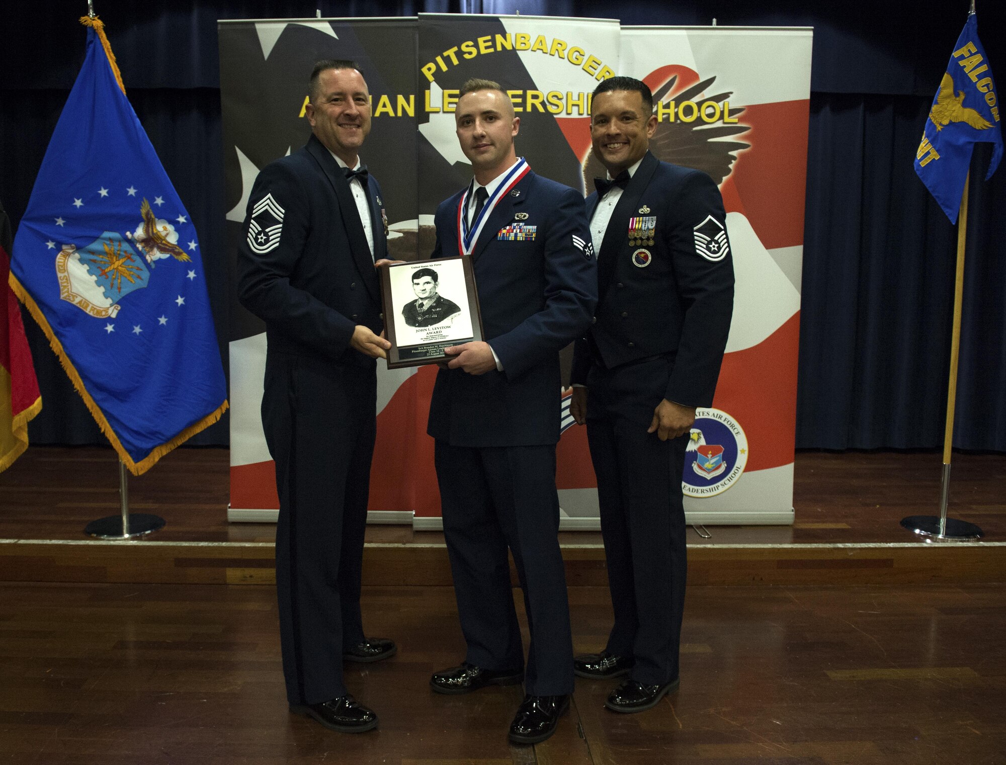 Senior Airman Brandon Hutchinson, 52nd Civil Engineer Squadron electrical systems journeyman, center, receives the John L. Levitow during the Pitsenbarger Airman Leadership School 16-F graduation at Club Eifel on Spangdahlem Air Base, Germany, Aug. 25, 2016. The Levitow award is the highest honor given to the student who displays excellence in all categories of ALS. (U.S. Air Force photo by Airman 1st Class Preston Cherry/Released)