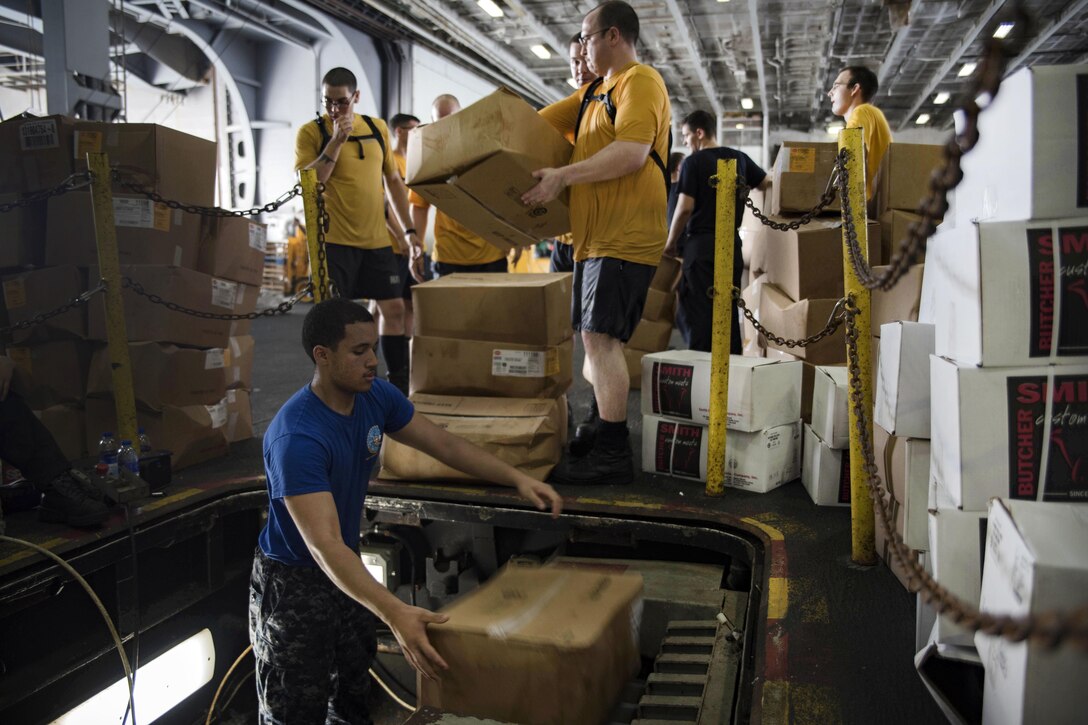 Sailors move cargo in the hangar bay of the aircraft carrier USS Dwight D. Eisenhower during a replenishment-at-sea with the fast combat support ship USNS Arctic in the Persian Gulf, Aug. 19, 2016. Navy photo by Seaman Apprentice Joshua Murray