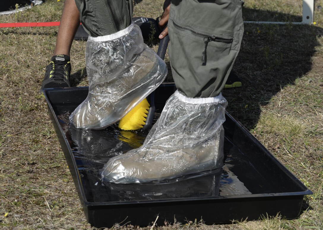 A 48th Fighter Wing flight crew member has his boots scrubbed as part of the decontamination process during an exercise at Royal Air Force Lakenheath, England, Aug. 23. Aircrew flight equipment technicians from every U.S. Air Forces in Europe base participated in the Chemical Defense Mobility Exercise to train on new procedures used to decontaminate aircrew. (U.S. Air Force photo/ Airman 1st Class Abby L. Finkel) 