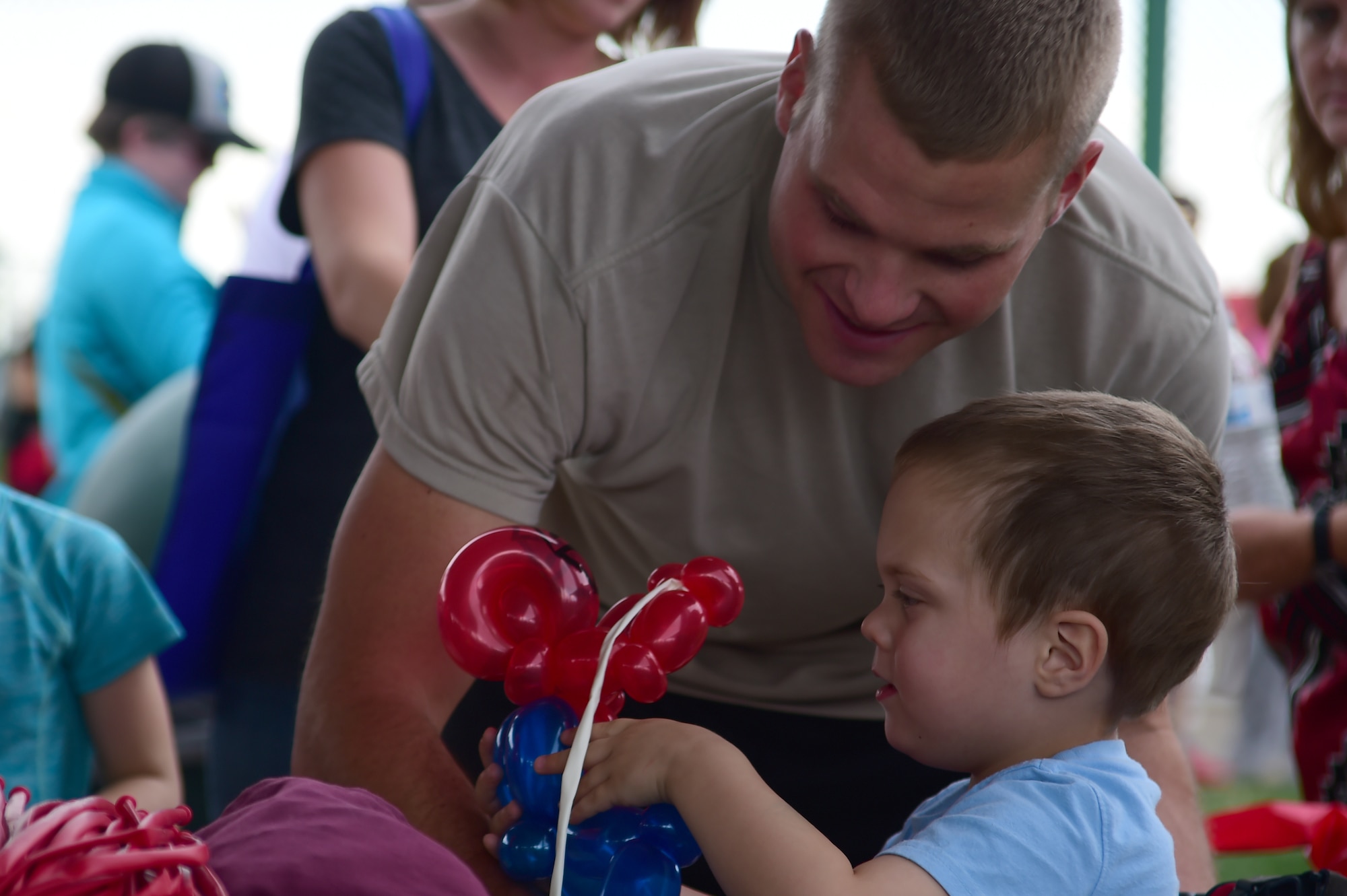 U.S. Army Sgt. Gary Andrews, 743rd Military Intelligence Battalion analyst, watches as his son James receives a balloon that has been sculpted to look like spiderman at FunFest Aug. 26, 2016, on Buckley Air Force Base, Colo. FunFest provides attraction for all ages and is an annual fair for the base community. (U.S. Air Force photo by Senior Airman Luke W. Nowakowski/Released)