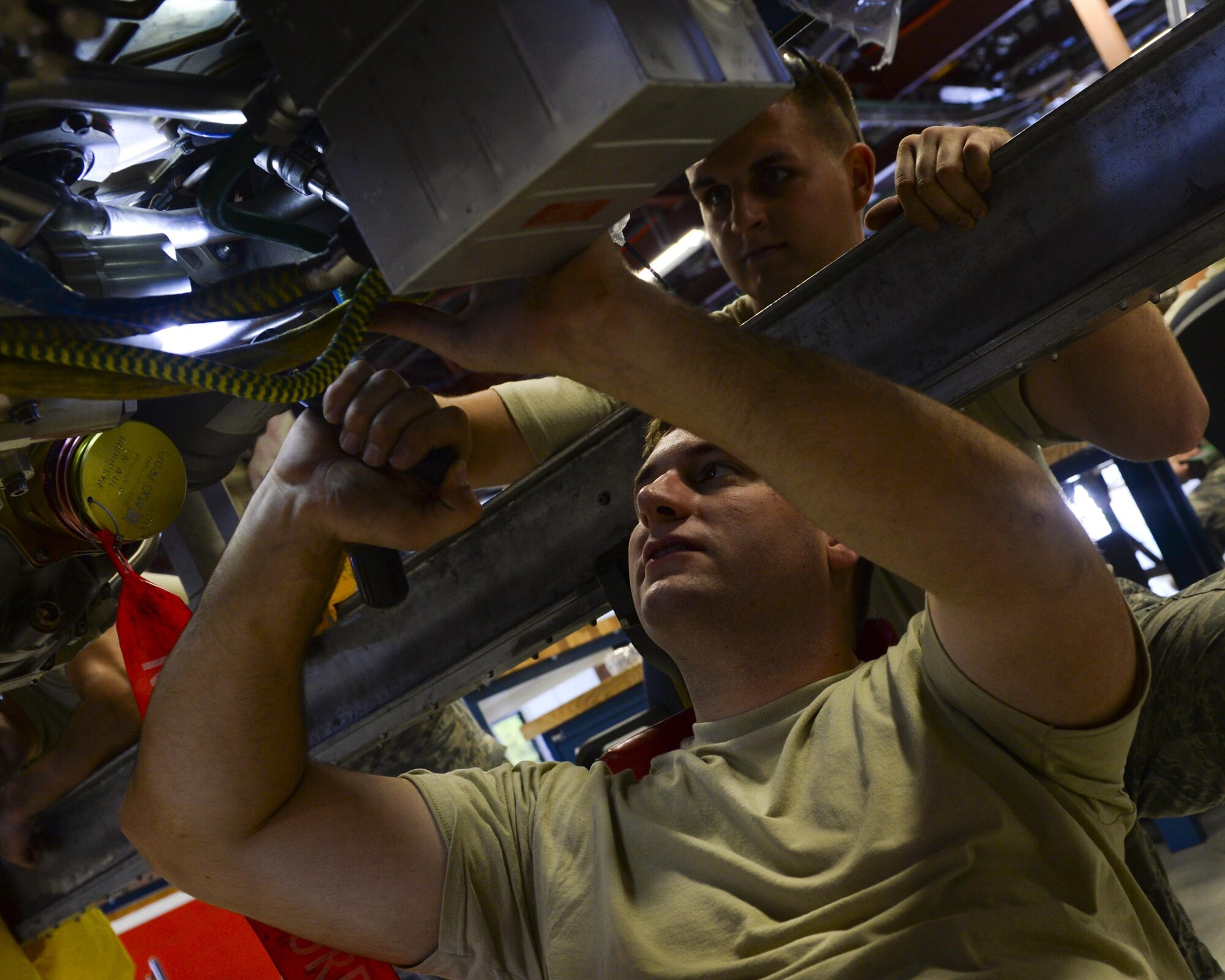 U.S. Air Force Staff Sgt. Cody Hammond, bottom, and Senior Airman Dwane Traynor, 325th Maintenance Squadron aerospace propulsion technicians, inspect the underside of an F-119 engine in the Propulsion Flight hangar at Tyndall Air Force Base, Fla., Aug. 29, 2016. Propulsion flight Airmen perform inspections to ensure the engines are safe for use in the F-22 Raptor. (U.S. Air Force photo by Airman 1st Class Cody R. Miller/Released)

