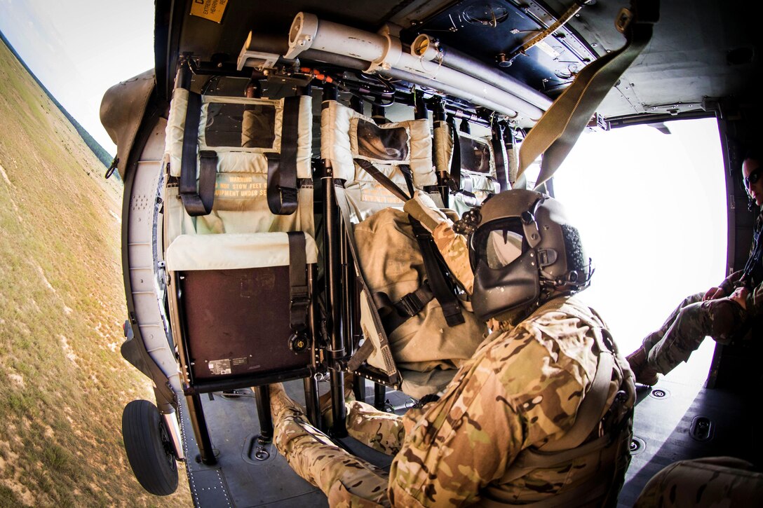 A soldier hangs on as a UH-60 Black Hawk helicopter maneuvers toward the Holland drop zone before participating in slingload training at Fort Bragg, N.C., Aug. 24, 2016. The soldier is a crew chief assigned to the 82nd Airborne Division’s 82nd Combat Aviation Brigade. Army photo by Capt. Adan Cazarez