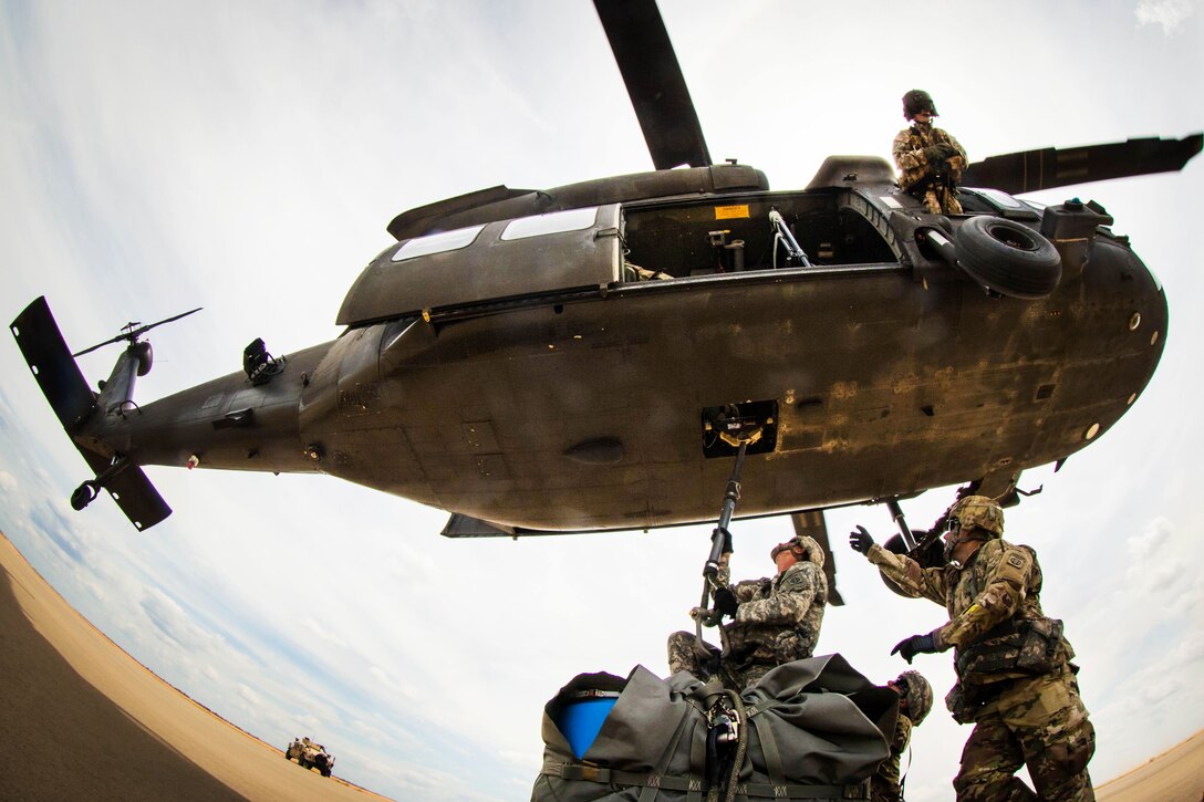 Soldiers attach a slingload hook onto a UH-60 Black Hawk helicopter during training on the Holland drop zone at Fort Bragg, N.C., Aug. 24, 2016. The soldiers are assigned to the XVIII Airborne Corps, Air Assault School. Army photo by Capt. Adan Cazarez