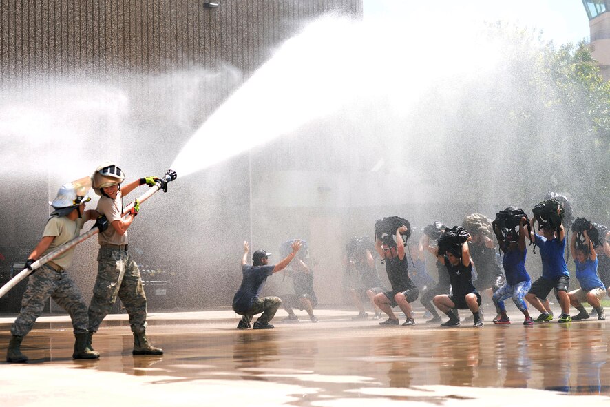 Laughlin firefighters spray Team Cohesion Challenge participants as they perform squats at the end of the challenge on Laughlin Air Force Base, Texas, Aug. 27, 2016. The teammates were faced with multiple challenges that tested teamwork and perseverance like rock climbing, a log carry and tire flipping, all during a four-mile ruck march. (U.S. Air Force photo/ Airman 1st Class Benjamin N. Valmoja)