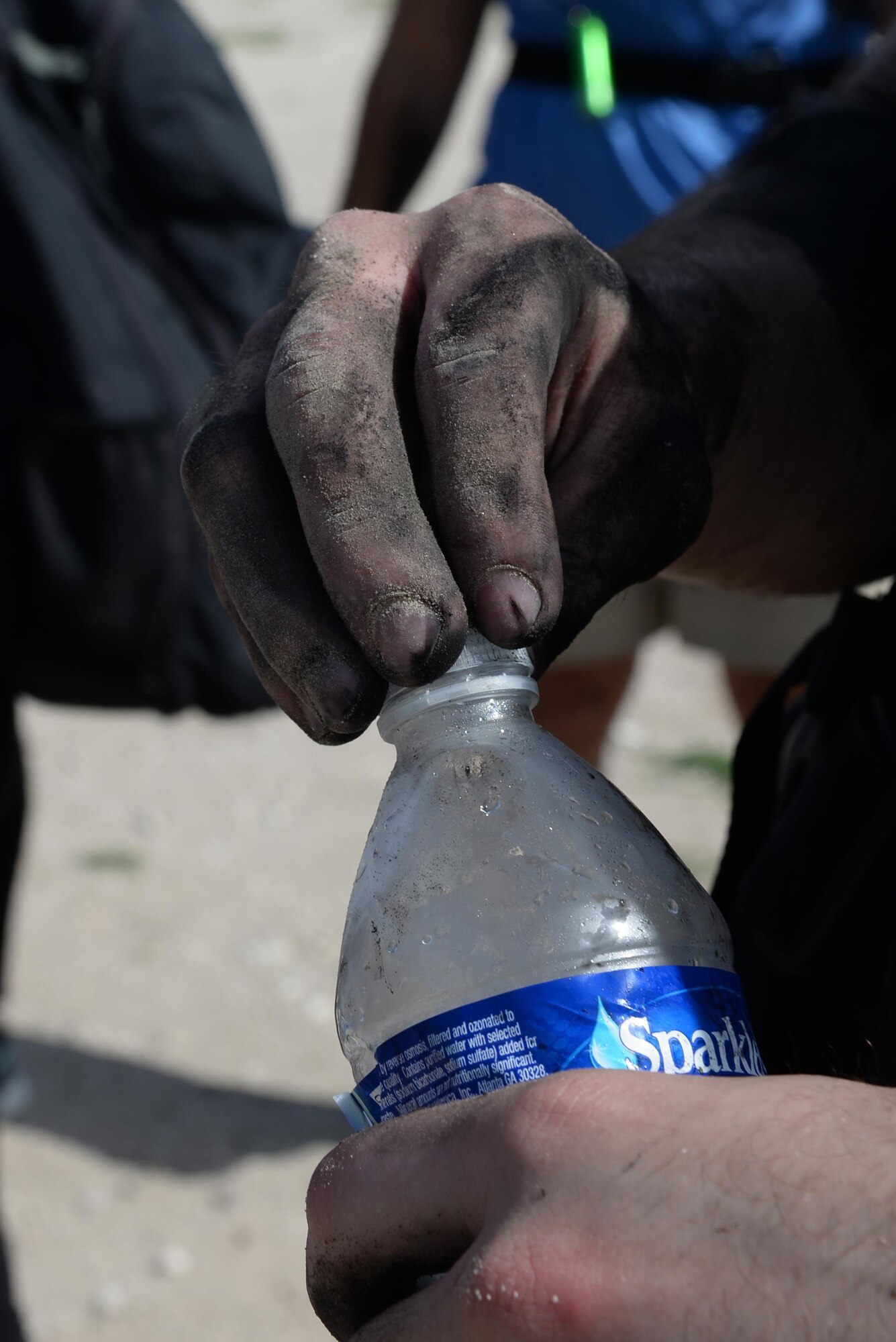 Airman Juan Loera, 47th Communications Squadron mobile knowledge operator, opens a water bottle after a tire-flipping challenge during the Team Cohesion Challenge on Laughlin Air Force Base, Texas, Aug. 27, 2016. The challenge, developed by GORUCK, was intended to exercise teamwork and push participants, and was modeled after special operations training. (U.S. Air Force photo/ Airman 1st Class Benjamin N. Valmoja)