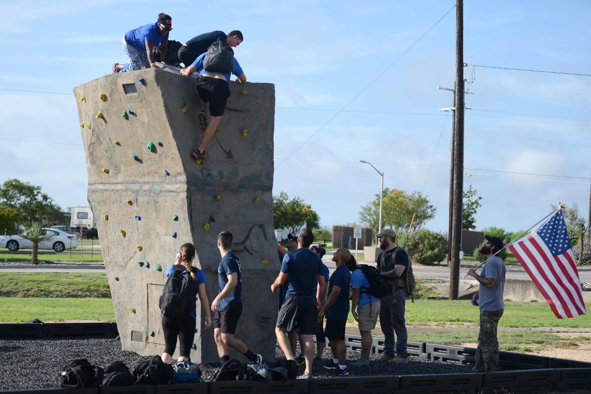 Members of Team XL transport themselves and their rucksacks over the base rock wall during the Team Cohesion Challenge on Laughlin Air Force Base, Texas, Aug. 27, 2016. Laughlin members were led through the challenge by cadre “CT”, far right, a prior Army Green Beret. (U.S. Air Force photo/Airman 1st Class Brandon May)