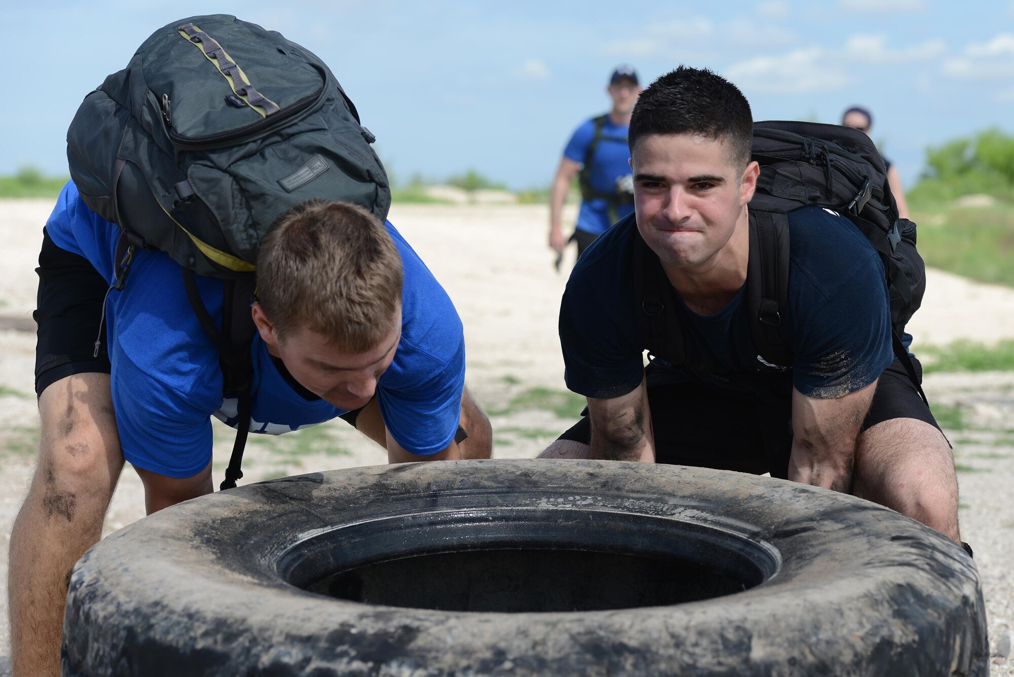Captain Kenneth Molleson, left, 47th Operations Support Squadron assistant operations officer, and Airman Juan Loera, 47th Communications Squadron mobile knowledge operator, flip a tire during the Team Cohesion Challenge on Laughlin Air Force Base, Texas, Aug. 27, 2016. Members of Laughlin participated in various team building challenges along the more than seven-mile ruck. (U.S. Air Force photo/Airman 1st Class Brandon May)