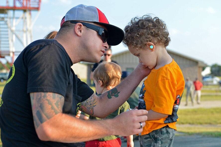 U.S. Air Force Tech. Sgt. James Fairbanks, 20th Aircraft Maintenance Squadron flightline expediter, puts hearing protection on his son at Poinsett Electronic Combat Range, Wedgefield, S.C., Aug. 26, 2016. The event gave Airmen and their families the opportunity to see the aerial capabilities of the the F-16CM Fighting Falcon in a controlled training environment. (U.S. Air Force photo by Airman 1st Class Christopher Maldonado)