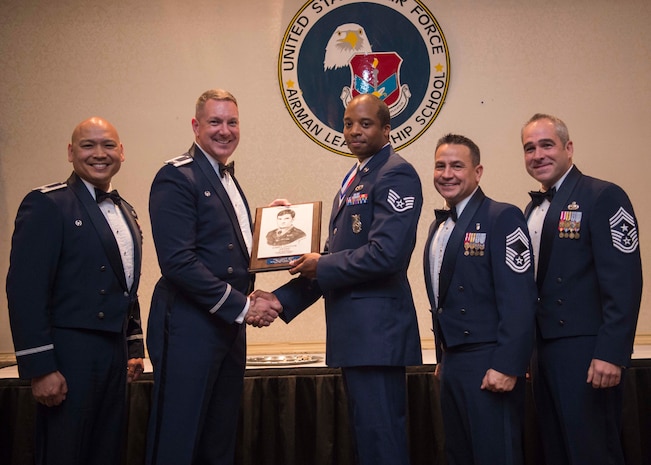 Staff Sgt. Christian Burt, 628th Civil Engineering Squadron fire protection journeyman (center), receives the John L. Levitow award from Col. Robert Lyman, 628th Air Base Wing commander (left), with Col. Jimmy Canlas, 437th Airlift Wing commander (far left), Chief Master Sgt. Chad Ballance, 628th ABW acting command chief (right) and Chief Master Sgt. Kristopher Berg, 437 AW command chief, during an Airman Leadership School graduation ceremony at the Charleston Club on Joint Base Charleston – Air Base, S.C., Aug. 25, 2016. The John L. Levitow Award is awarded to a single graduate for every Enlisted Professional Military Education course for demonstrating excellence both as a leader and scholar. (U.S. Air Force photo/Airman 1st Class Thomas T. Charlton)