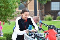 Christine Pasun, 50th Operations Support Squadron, unfastens her bicycle helmet as she prepares to begin the bicycle portion of the 12th annual Schriever Air Force Base Triathlon at Schriever Air Force Base, Colorado, Friday, Aug. 26, 2016. Pasun garnered the top time for females, finishing the event in 1:35:23. (U.S. Air Force photo/Brian Hagberg)