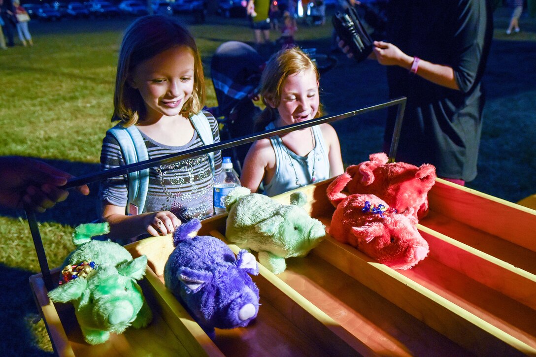 Two members of Team Seymour watch as mechanical pigs race to the finish line, Aug. 26, 2016, at Seymour Johnson Air Force Base, North Carolina. The postponed Independence Day celebration featured live music, food vendors, and game stations, followed by a firework show to end the night. (U.S. Air Force photo by Airman Shawna L. Keyes)