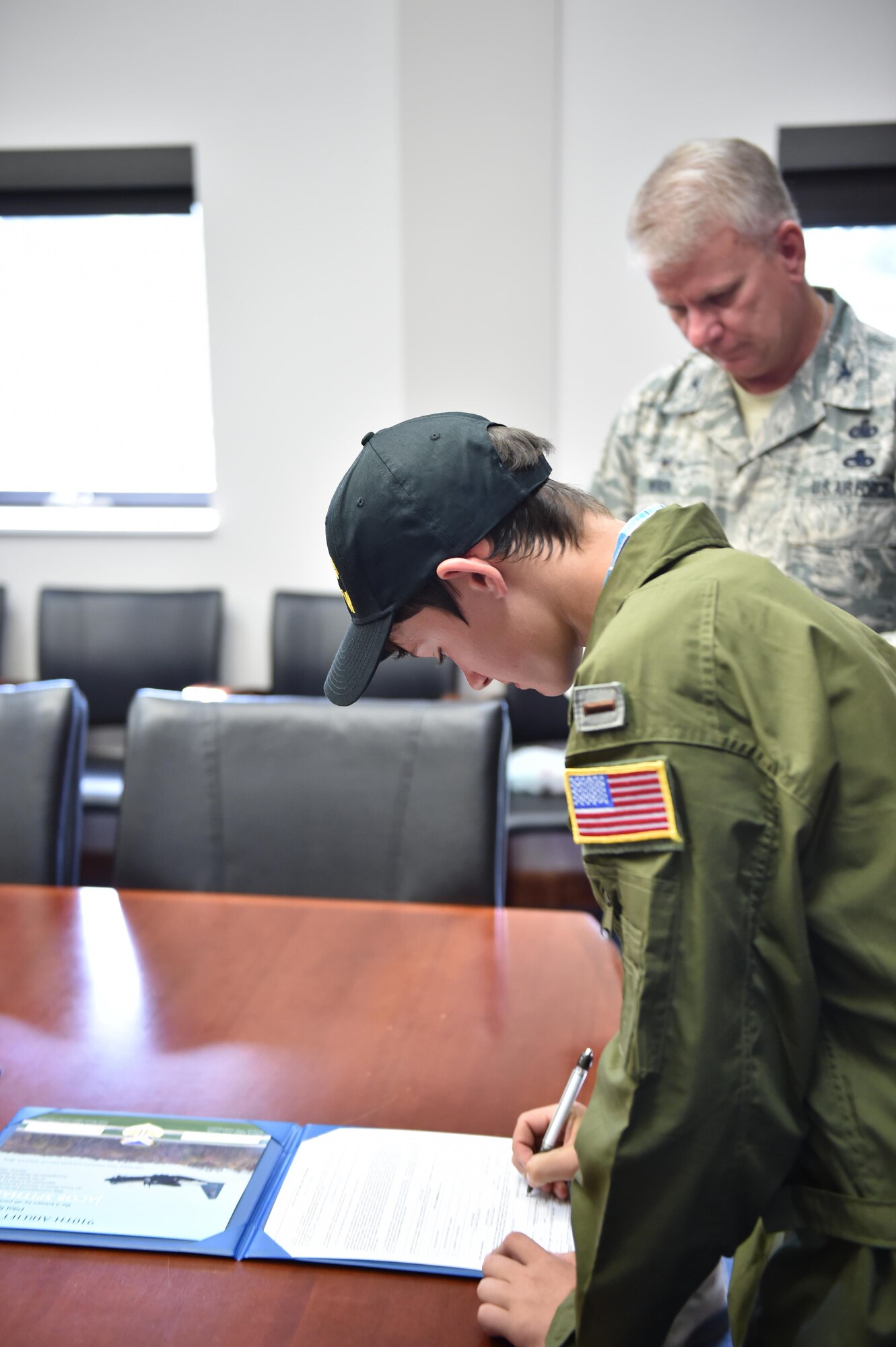 Jacob Spithaler, 14, signs his commissioning paperwork as Col. Don Wren, 910th Mission Support Group commander, looks on here, Aug. 24, 2016. Spithaler was the 64th honoree of the 910th Airlift Wing’s Pilot for a Day Program in which children with chronic or life-threatening illnesses are welcomed to the station, commissioned as honorary second lieutenants and treated to a day fun military themed activities. Wren led Spithaler in a commissioning ceremony as 910th Airmen, local media representatives, staff from Akron Children's Hospital's Boardman campus and some of Jacob's friends and family members observed. (U.S. Air Force photo/Eric White)