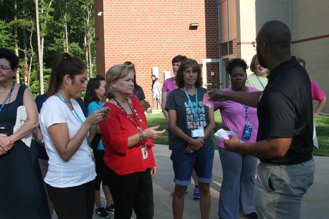 Marine Corps Base Quantico School Liaison Chris Lamb hands out family member assignments to teachers at Kyle Wilson Elementary School in Prince William County Aug. 24. The teachers were participating in a "PCS Challenge" facilitated by the MCBQ and Fort Belvoir school liaisons in order to better understand what military children experience moving from duty station to duty station. Each group of teachers role-played a military family being assigned to a new post.