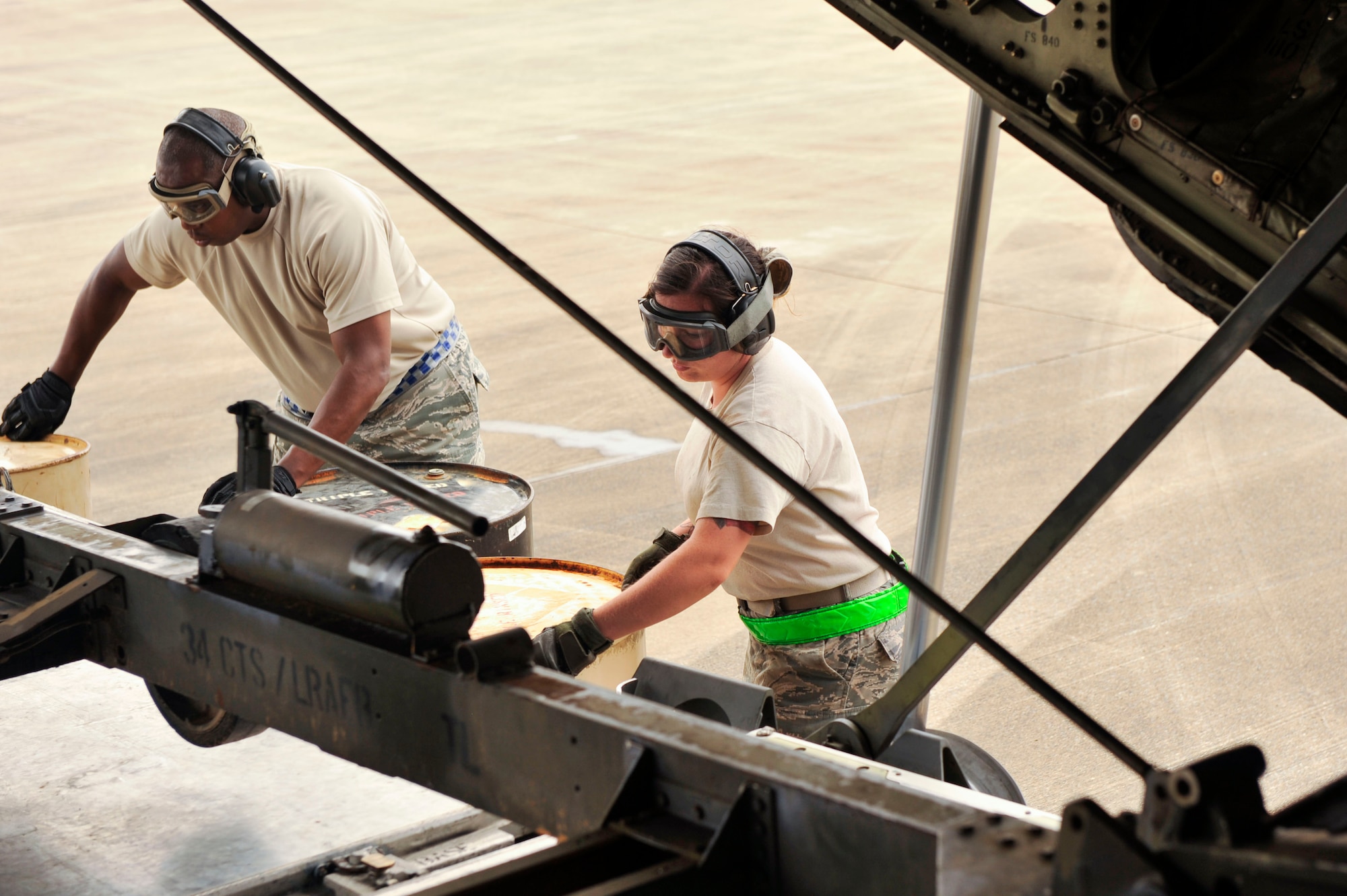 Airmen from the 305th Aerial Port Squadron at Joint Base McGuire-Dix-Lakehurst, New Jersey, load barrels under a trailer carrying a 1,430-lb. C-130 engine stand trailer unit Aug. 26, 2016, at a landing zone in Alexandria, Louisiana. The barrels are used to support the pallet as the C-130 slowly pulls forward to release the equipment. (U.S. Air Force photo by Staff Sgt. Regina Edwards)