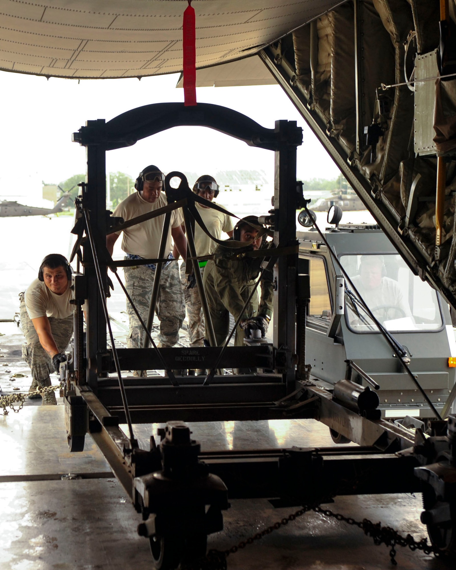 Loadmasters from the 41st Airlift Squadron from Little Rock Air Force Base, Ark., assist Airmen from the 305th Aerial Port Squadron at Joint Base McGuire-Dix-Lakehurst, New Jersey, loading a C-130 engine stand trailer unit Aug. 26, 2016, at a landing zone in Alexandria, Louisiana. The 1,430-lb. trailer is used to safely transport an aircraft’s engine from the runway to a maintenance bay to allow more precise repairs. (U.S. Air Force photo by Staff Sgt. Regina Edwards) 